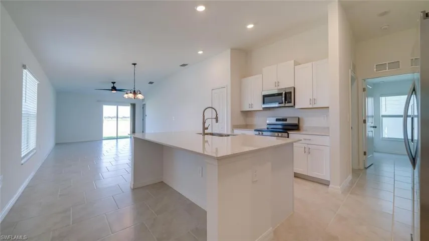 Kitchen featuring stainless steel appliances, an island with sink, light tile patterned flooring, and sink