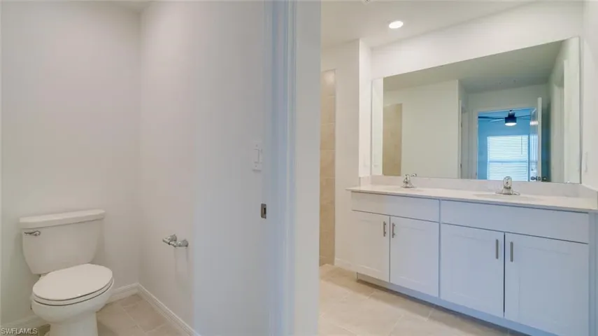 Bathroom featuring vanity, toilet, ceiling fan, and tile patterned floors
