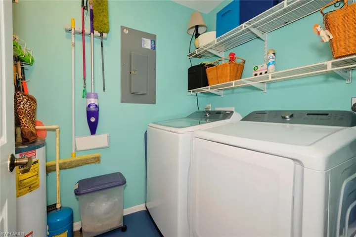 Laundry room with electric panel, water heater, and washing machine and dryer