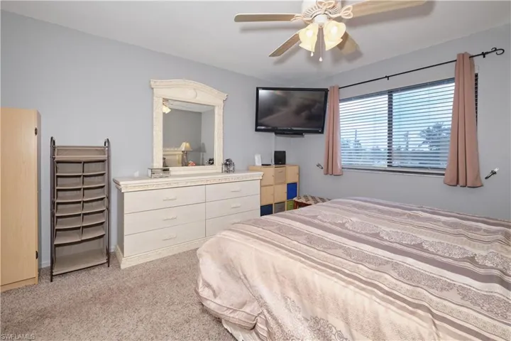 Bedroom with light colored carpet and a ceiling fan