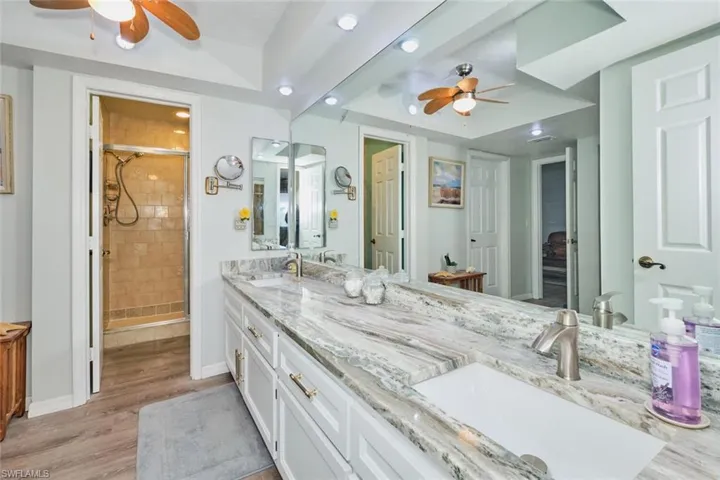 Bathroom featuring ceiling fan, a stall shower, double vanity, recessed lighting, and light wood-style flooring