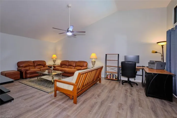 Living room featuring an office area, vaulted ceiling, light wood-style floors, and ceiling fan