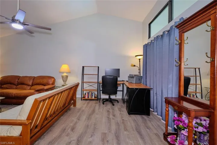 Office space with light wood-style floors, lofted ceiling, and a ceiling fan