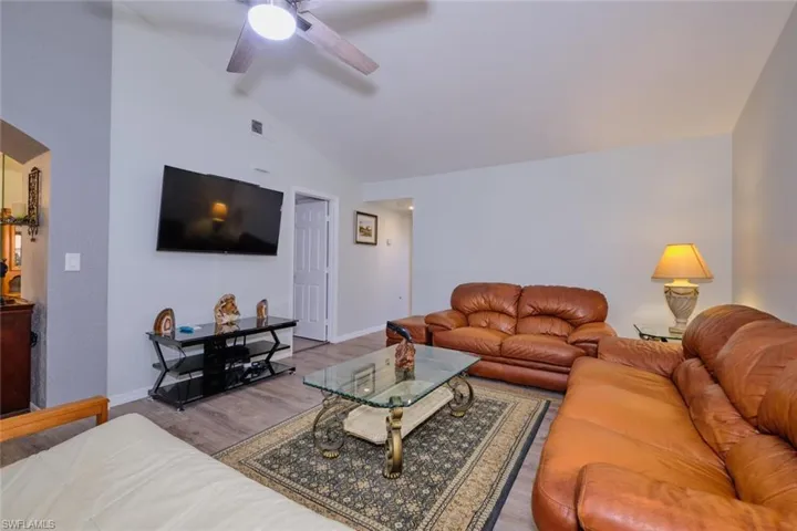 Living room featuring vaulted ceiling, wood finished floors, and ceiling fan