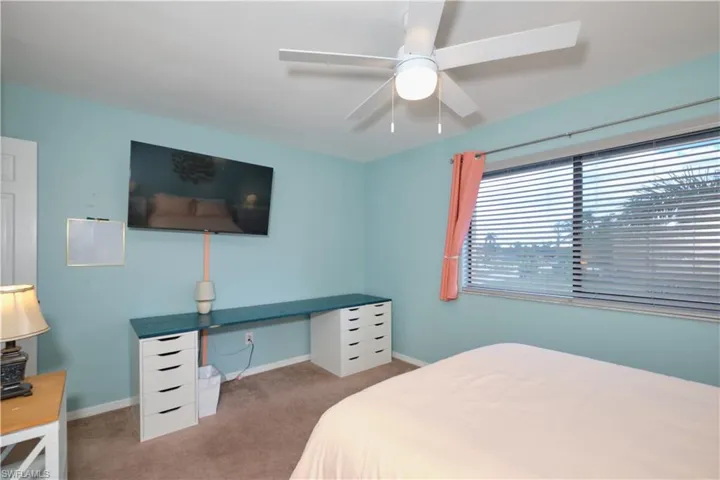 Carpeted bedroom with ceiling fan and a desk