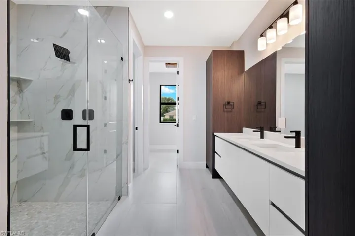Full bath featuring double vanity, a marble finish shower, and recessed lighting