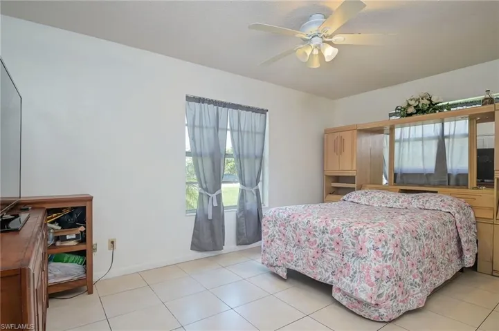 Tiled bedroom featuring ceiling fan