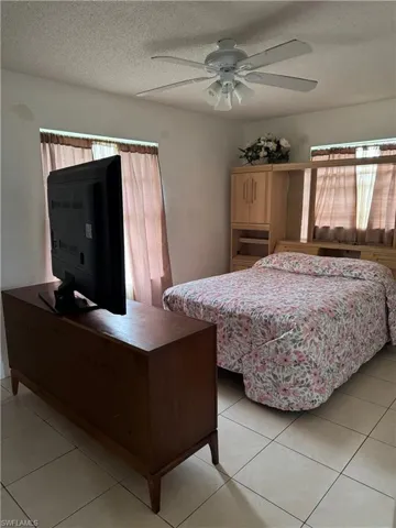 Bedroom featuring ceiling fan, light tile patterned floors, and a textured ceiling