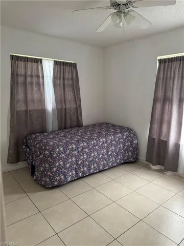 Tiled bedroom featuring ceiling fan and a textured ceiling