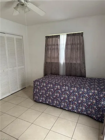 Unfurnished bedroom with ceiling fan, a closet, and light tile patterned floors