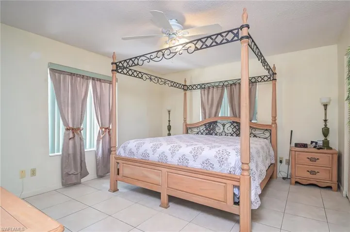 Tiled bedroom featuring ceiling fan and a textured ceiling