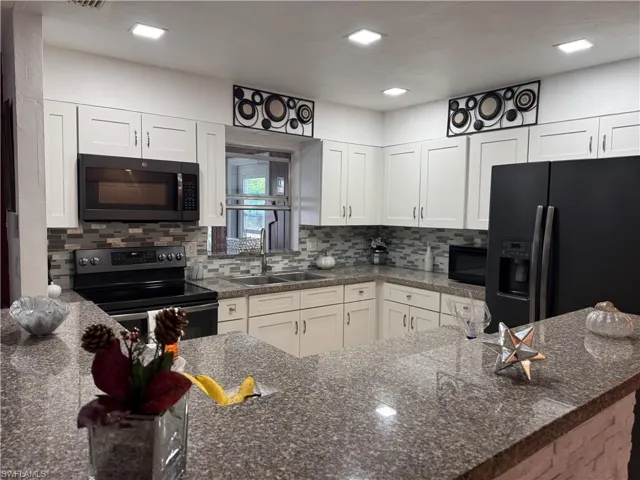 Kitchen with white cabinetry, sink, and black appliances