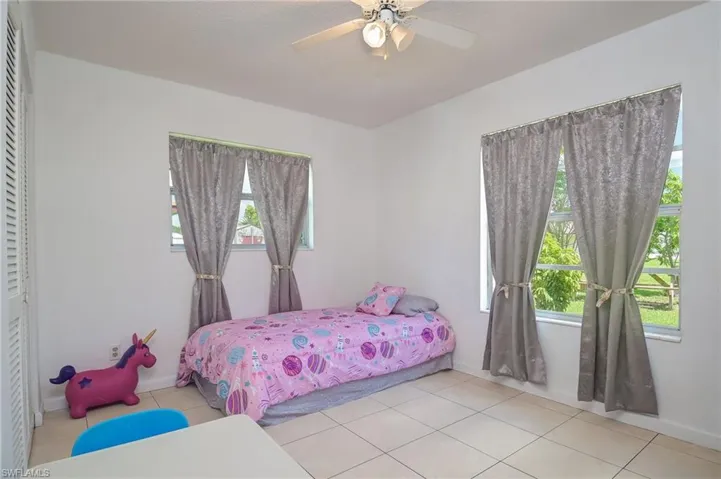 Tiled bedroom featuring ceiling fan and a closet