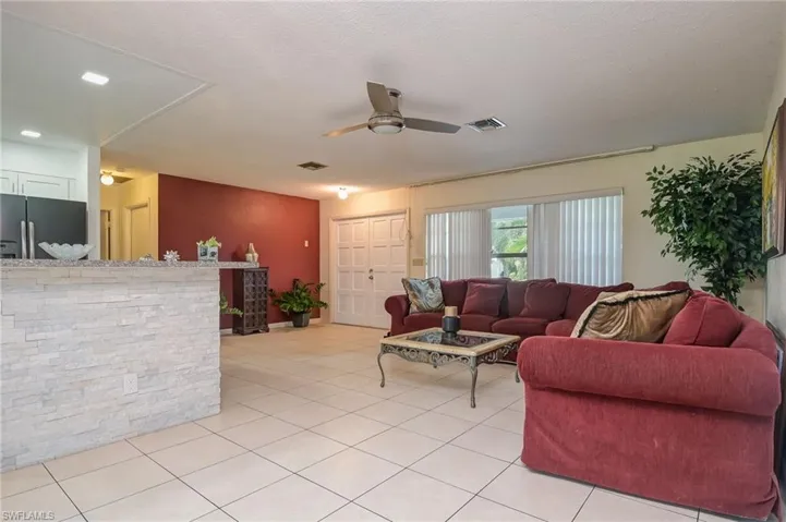 Living room with a textured ceiling, light tile patterned floors, and ceiling fan