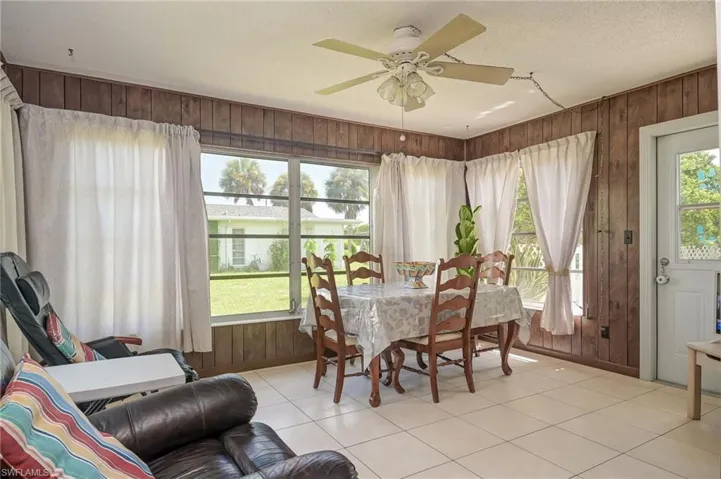 Tiled dining room featuring wooden walls, ceiling fan, and a textured ceiling
