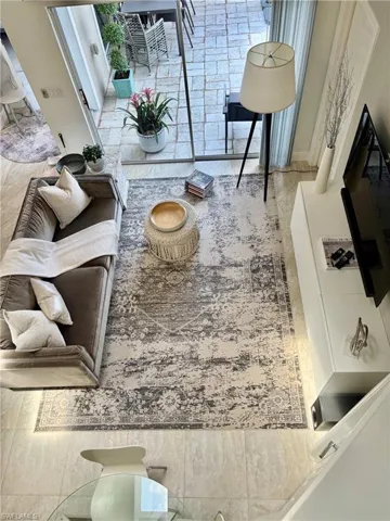 Spacious living area featuring light-toned tile flooring throughout and a full-height glass sliding door