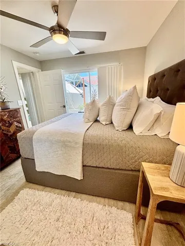 Room featuring wood-finish flooring, a ceiling fan with integrated lighting, and a dark upholstered headboard
