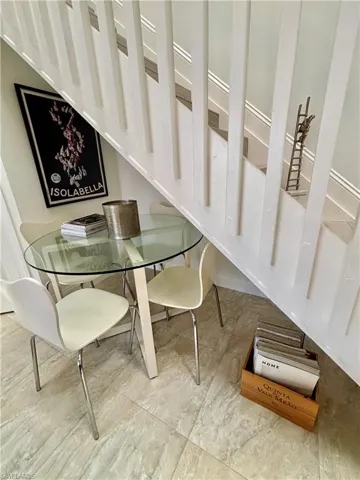 Under-stair alcove featuring light-toned tile flooring and a glass-top table