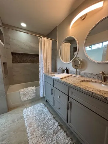 Bathroom featuring a dual vanity with a speckled countertop, undermount sinks, and grey cabinetry