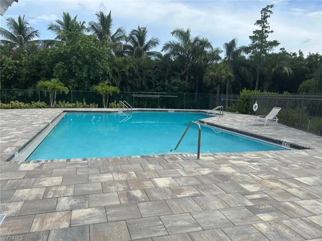 Rectangular swimming pool featuring a light blue finish, surrounded by multi-toned paver decking