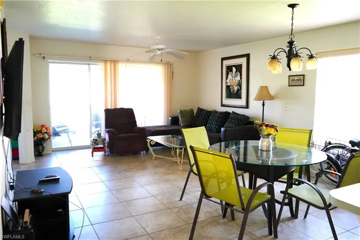 Tiled dining area featuring ceiling fan with notable chandelier