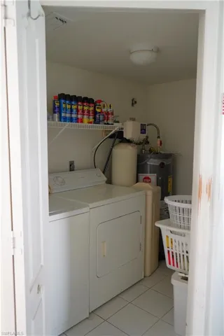 Clothes washing area featuring independent washer and dryer, hookup for an electric dryer, electric water heater, and light tile floors