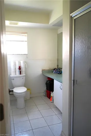 Bathroom with a shower with door, tile flooring, vanity, and toilet