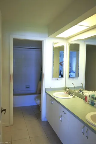 Full bathroom with double sink vanity, tile flooring, tiled shower / bath, and toilet