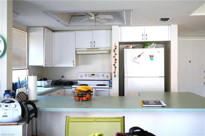 Kitchen with white cabinets, ceiling fan, and white appliances