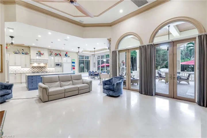 Living area featuring french doors, a towering ceiling, ceiling fan, ornamental molding, and recessed lighting