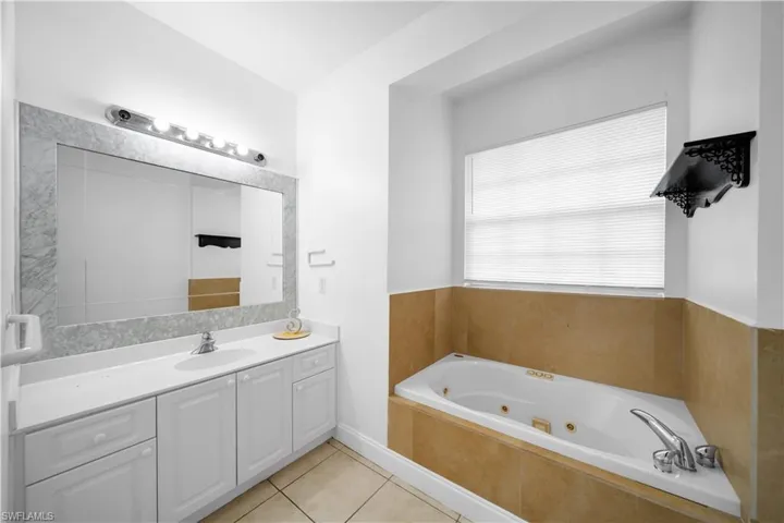 Full bathroom featuring tile patterned flooring, a jetted tub, and vanity