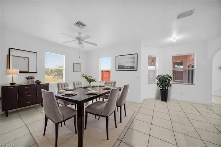 Dining area featuring arched walkways, light tile patterned floors, and visible vents