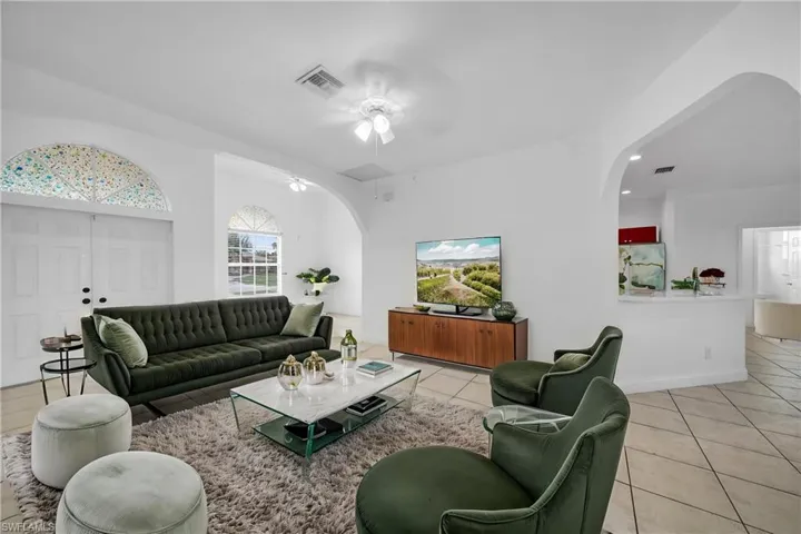 Living area featuring visible vents, arched walkways, a ceiling fan, and light tile patterned flooring