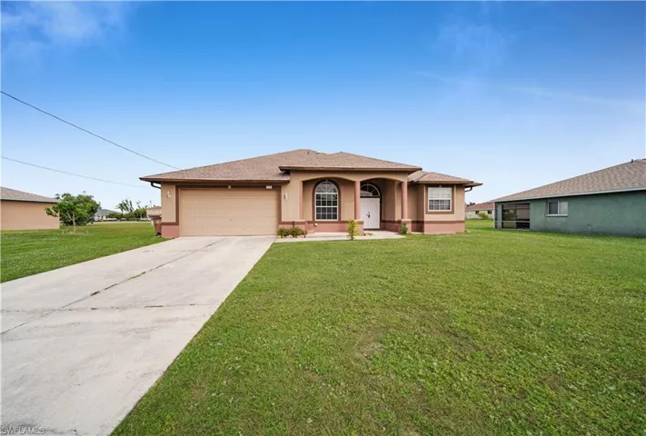 View of front of property featuring a front yard, driveway, an attached garage, and stucco siding