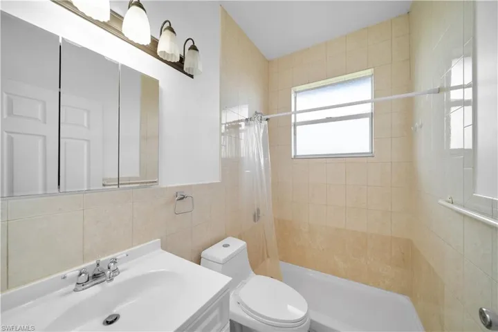 Full bath with toilet, a shower stall, tile walls, and vanity