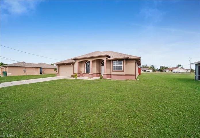 View of front of property featuring driveway, an attached garage, a front yard, and stucco siding