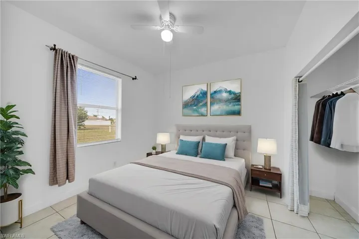 Bedroom with light tile patterned floors, ceiling fan, and baseboards