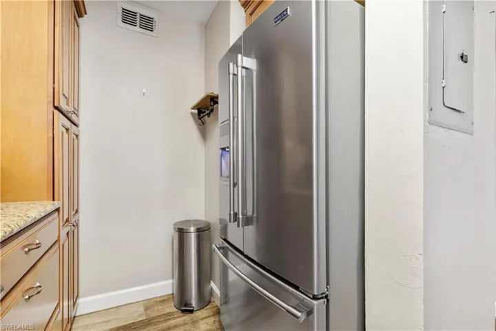 Kitchen with light hardwood / wood-style floors and high quality fridge
