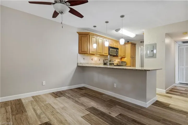 Kitchen with hanging light fixtures, light hardwood / wood-style floors, kitchen peninsula, and backsplash