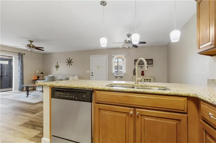 Kitchen featuring decorative light fixtures, dishwasher, ceiling fan, light wood-type flooring, and sink