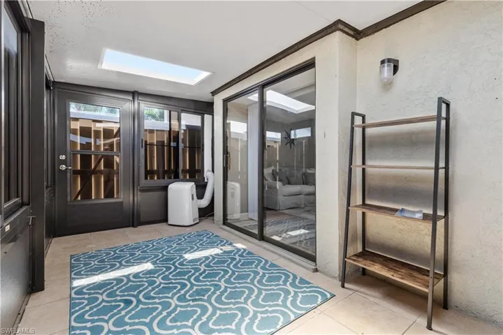 Entrance foyer with light tile floors, crown molding, and a skylight