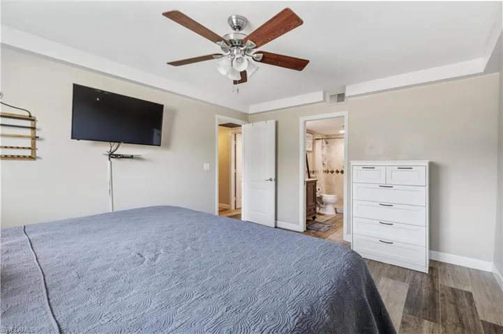 Bedroom featuring dark hardwood / wood-style floors, ceiling fan, and connected bathroom