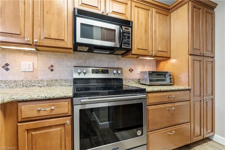 Kitchen with stainless steel appliances, light stone counters, and backsplash