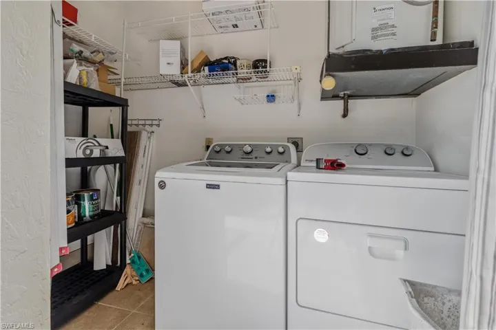 Clothes washing area with washer and dryer and light tile floors