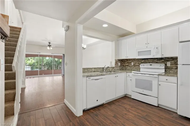 White kitchen featuring granite countertops and a tiled backsplash