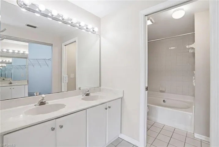 Dual vanity with integrated sinks, white cabinetry, and a large wall-mounted mirror