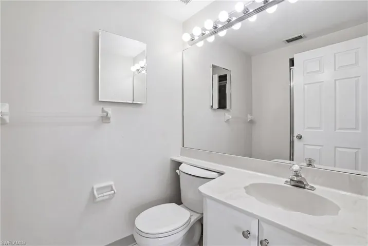 Bathroom vanity with an integrated sink, polished chrome faucet, and a large wall-mounted mirror