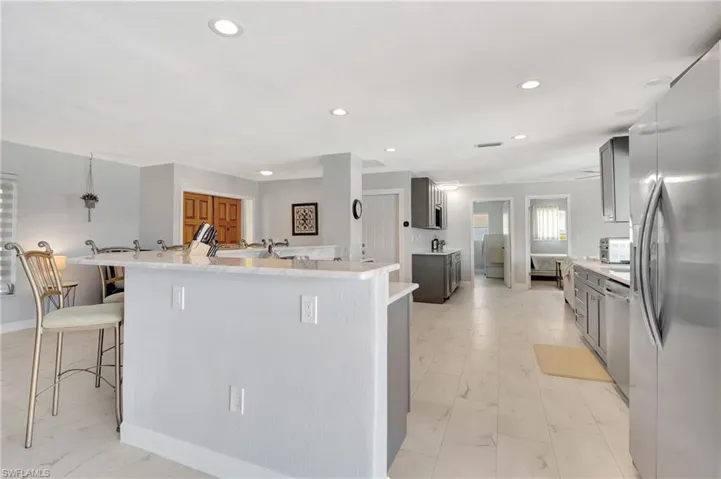 Kitchen featuring gray cabinetry, a breakfast bar, light tile patterned floors, and stainless steel appliances