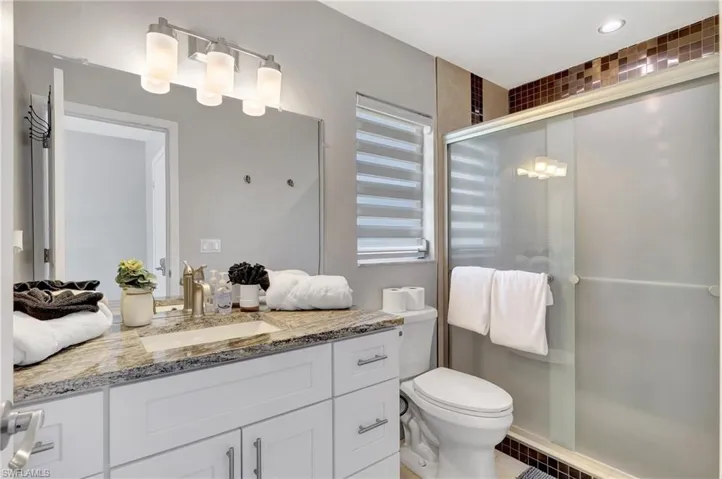 Bathroom with vanity, an enclosed shower, and toilet