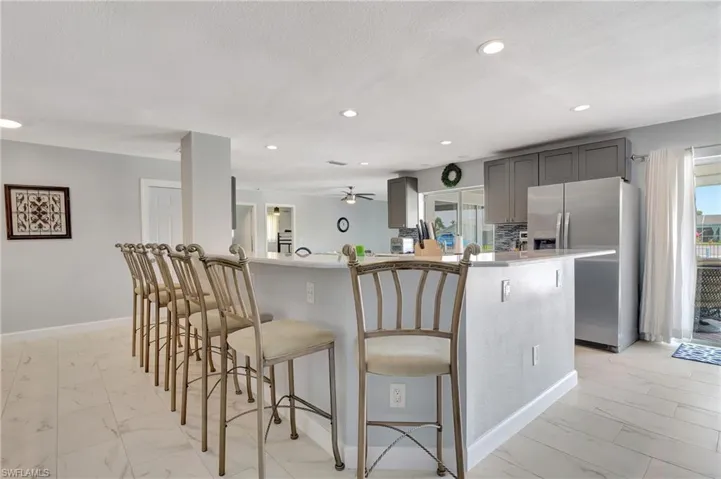 Kitchen featuring light tile patterned flooring, ceiling fan, stainless steel refrigerator with ice dispenser, kitchen peninsula, and gray cabinetry